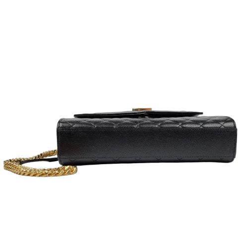 Black quilted handbag with gold chain on a light gray background