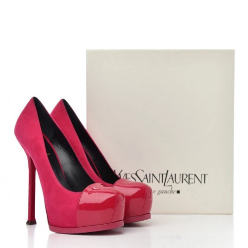 A pair of bright pink high-heeled pumps with black trim and a black interior, displayed next to a white Giorgio Armani box on a white background.